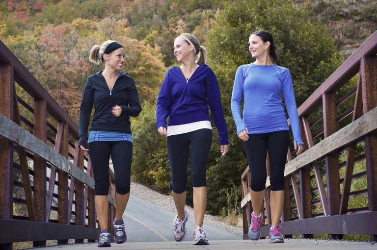 Three women walking together on a small bridge
