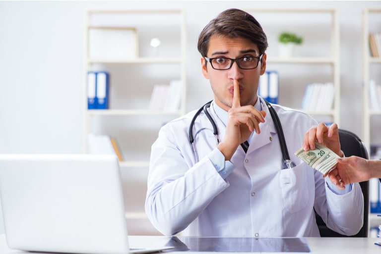 A physician colleting cash while his body language expresses the sentiment to keep quiet